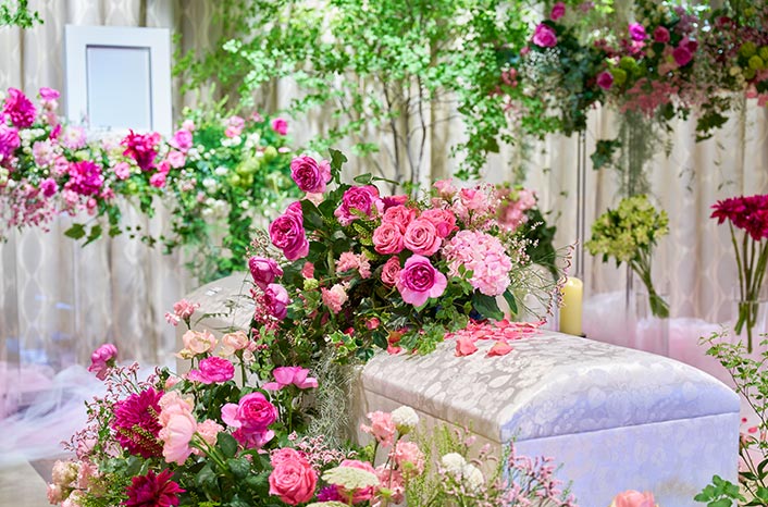 棺の周りにはピンクや赤を基調とした花がたくさん飾られています