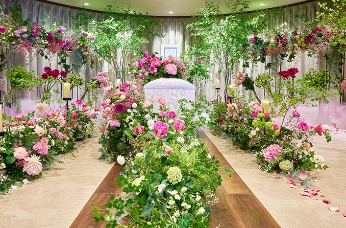 棺の周りにはピンク、赤、緑などの花や葉ががたくさん飾られています