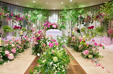 棺の周りにはピンク、赤、緑などの花や葉ががたくさん飾られています