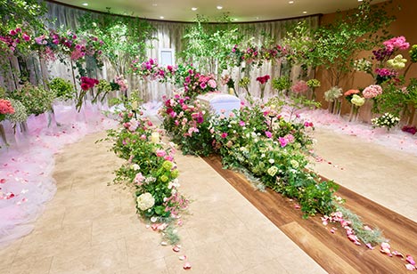 棺が置かれ、周りにはピンク、赤、緑などの花や葉ががたくさん飾られています